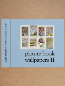 Foto mostrando a capa do catálogo de opções de papel de parede chamado Picture Books Wallpapers II de John Derian para Designer Guild. A capa é azul clara com algumas imagens retangulares das estampas.